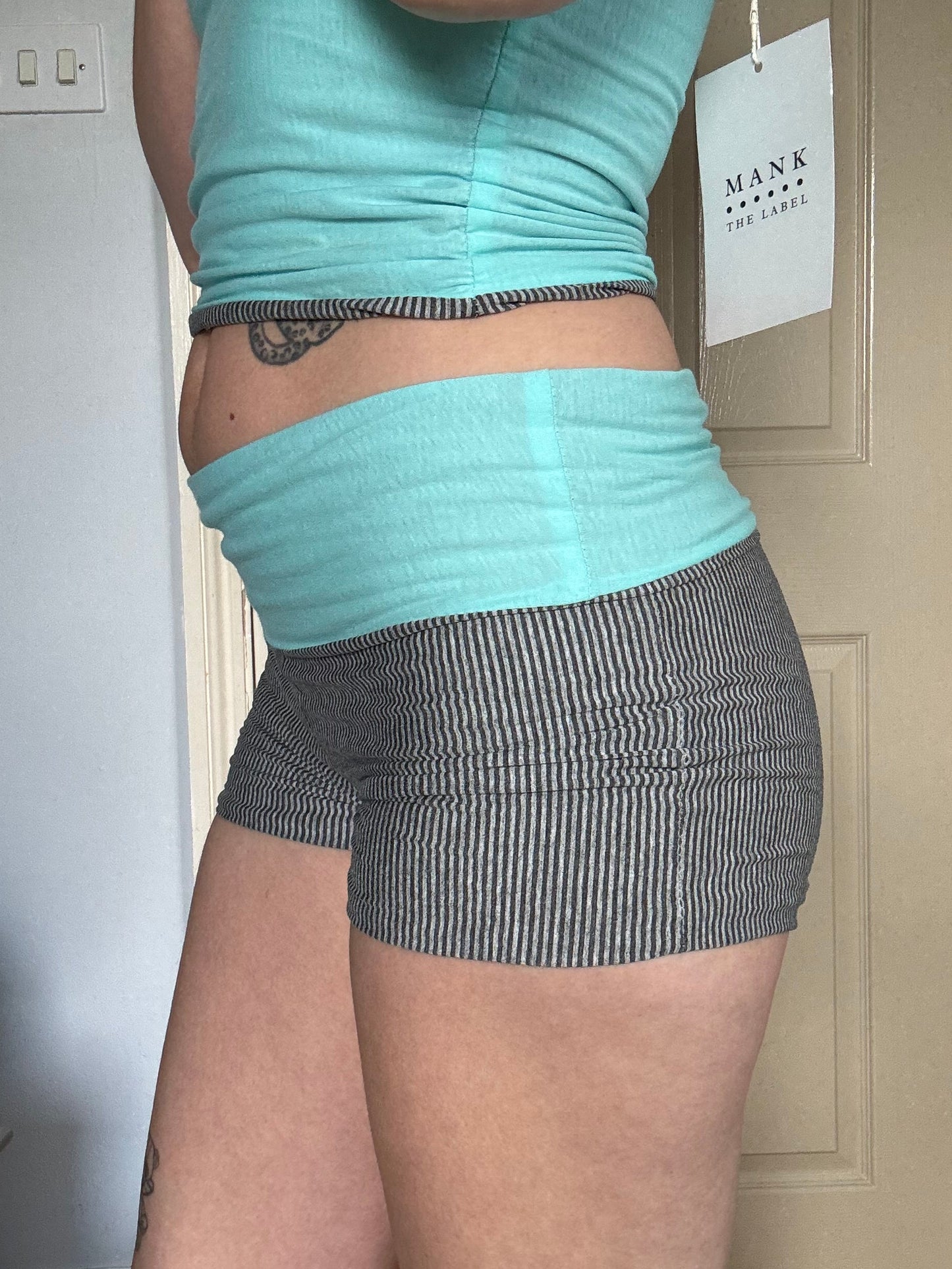 Person wearing a light blue and grey stripe reversible shorts with wide waistband.