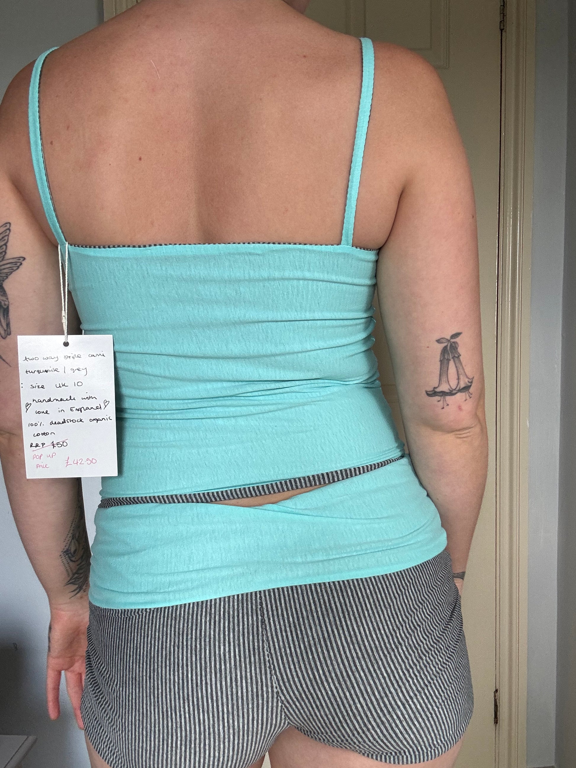 Person wearing a light blue / turquoise and grey stripe reversible tank top.