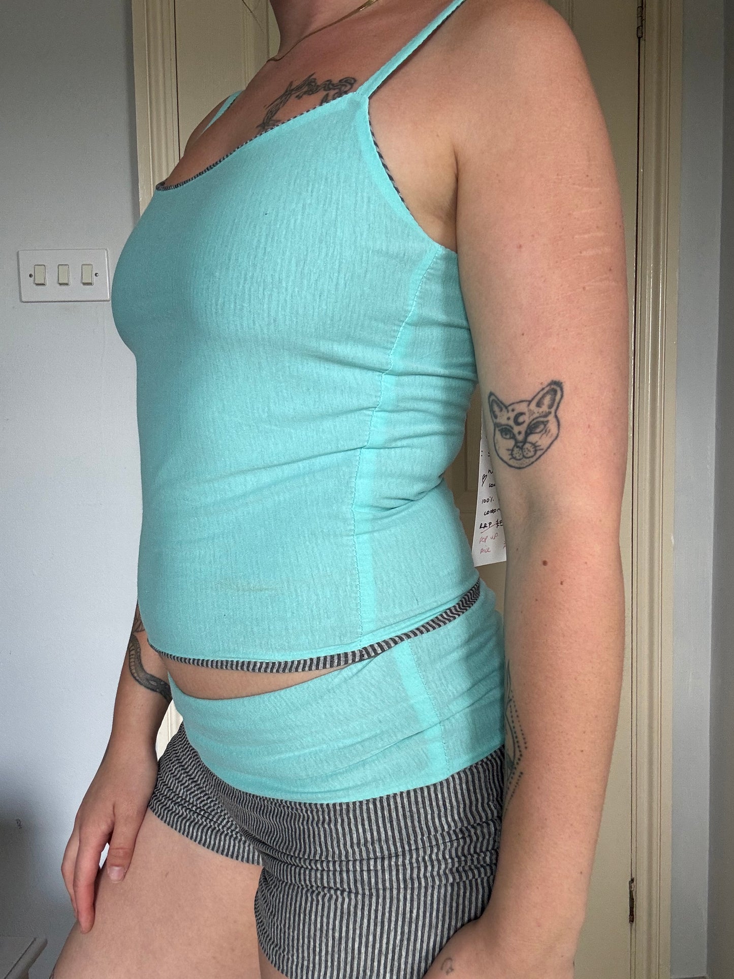 Person wearing a light blue / turquoise and grey stripe reversible tank top.