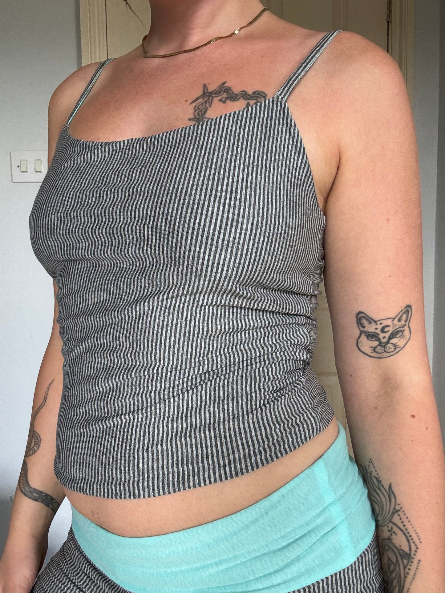 Person wearing a light blue / turquoise and grey stripe reversible tank top.