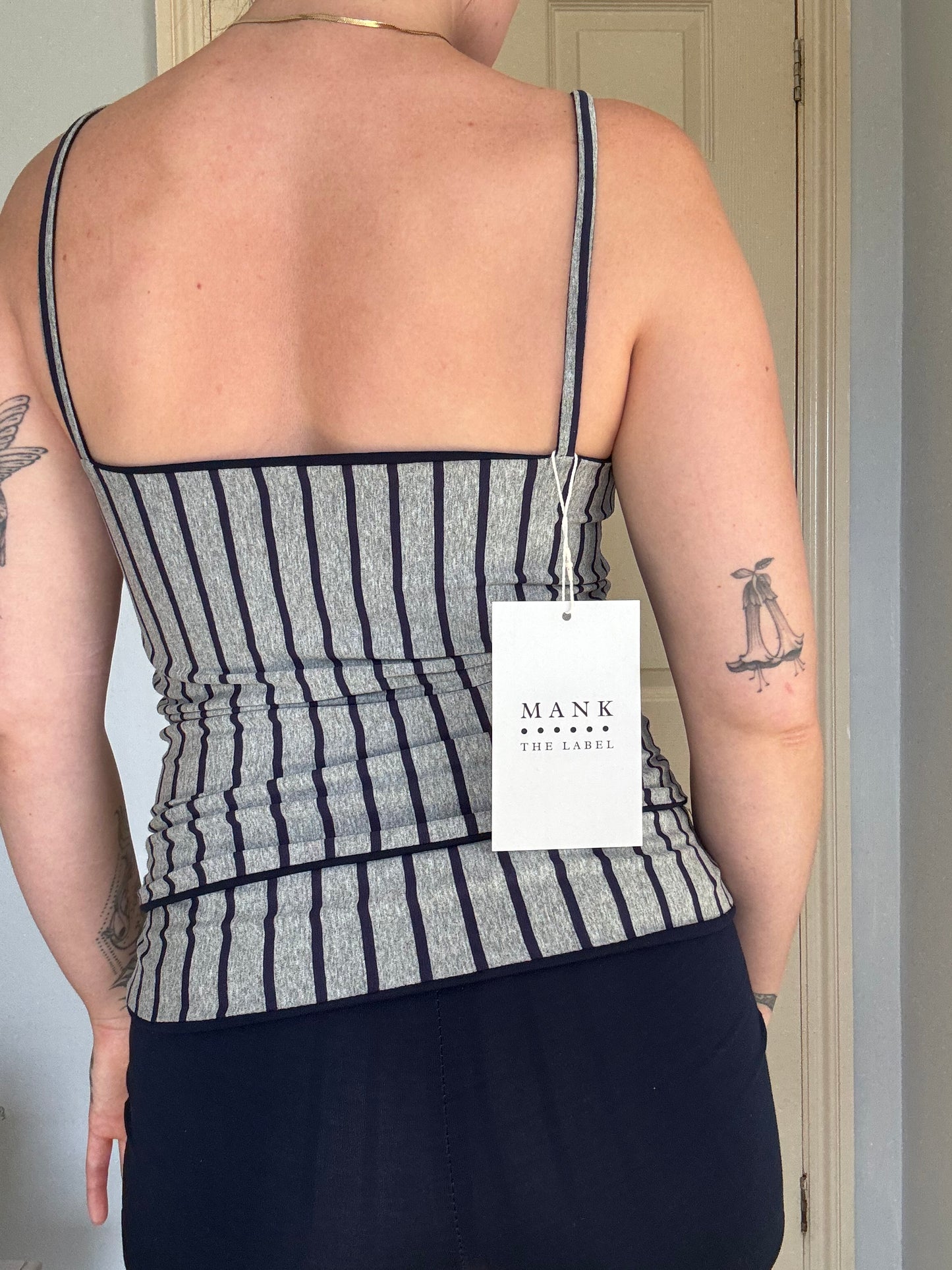 Person wearing a navy blue and grey stripe reversible tank top.