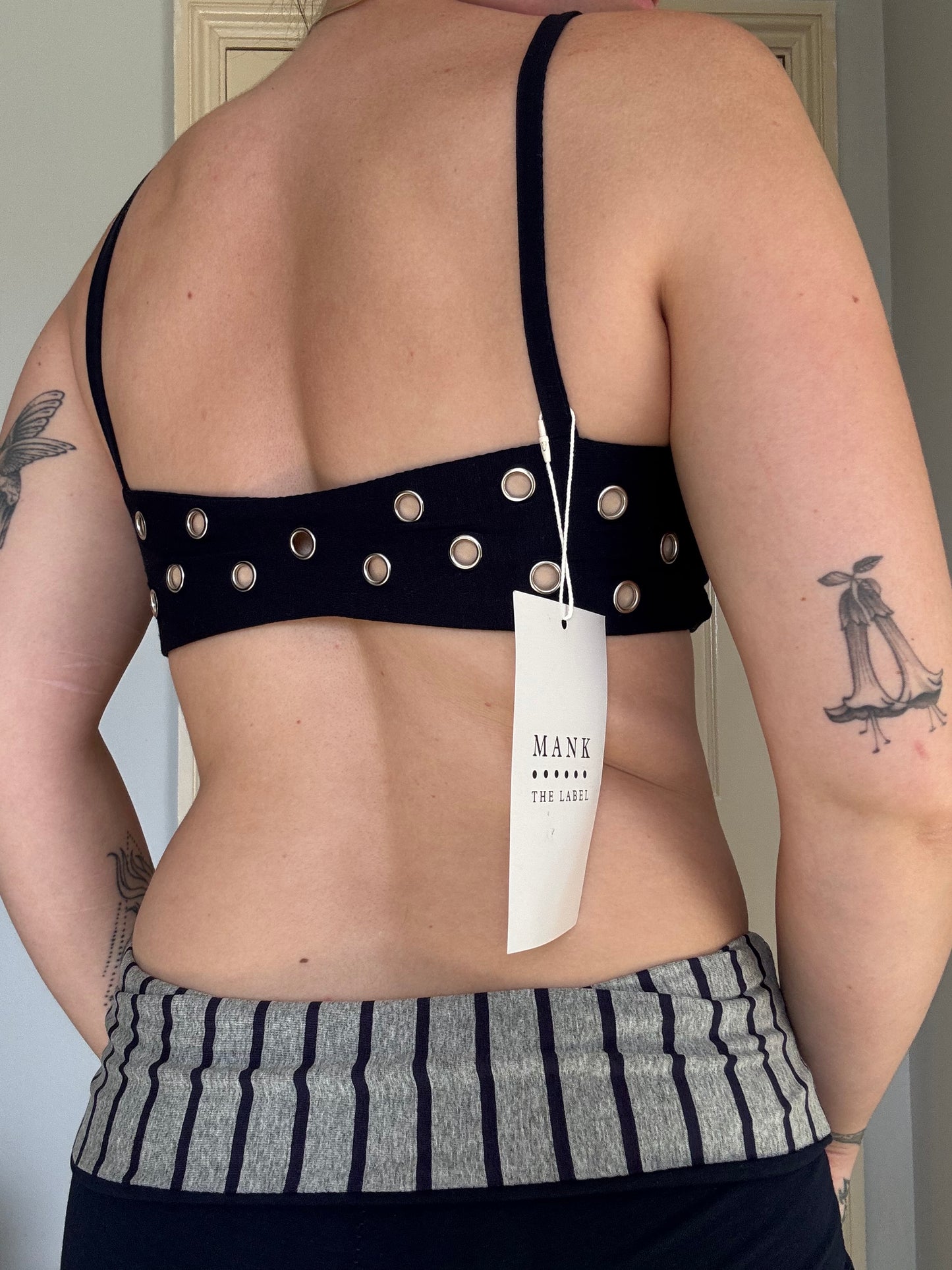 person wearing a navy blue stretchy eyelet bralet with hanging brand tag.