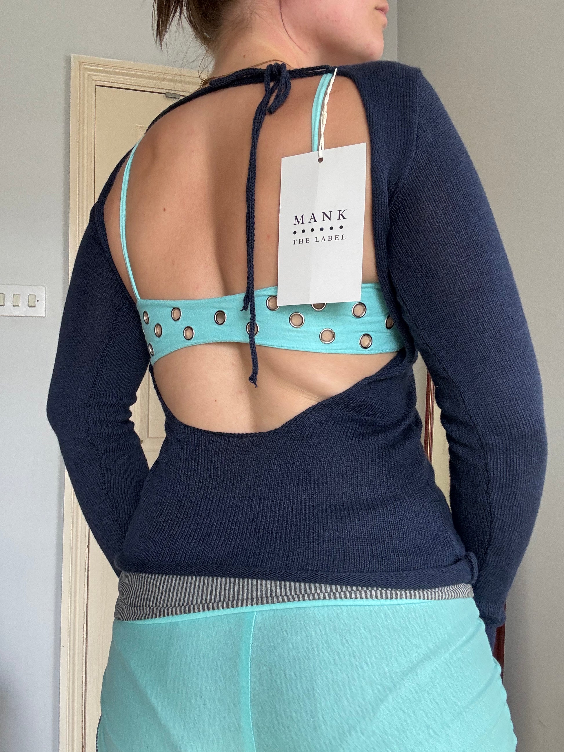 Person wearing a backless navy blue long sleeve cotton knit top over  turquoise eyelet bralet.