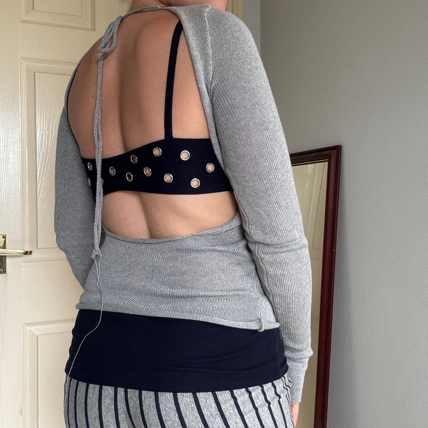 Person wearing a gray knit long sleeve backless top with striped shorts & navy blue eyelet bralet.