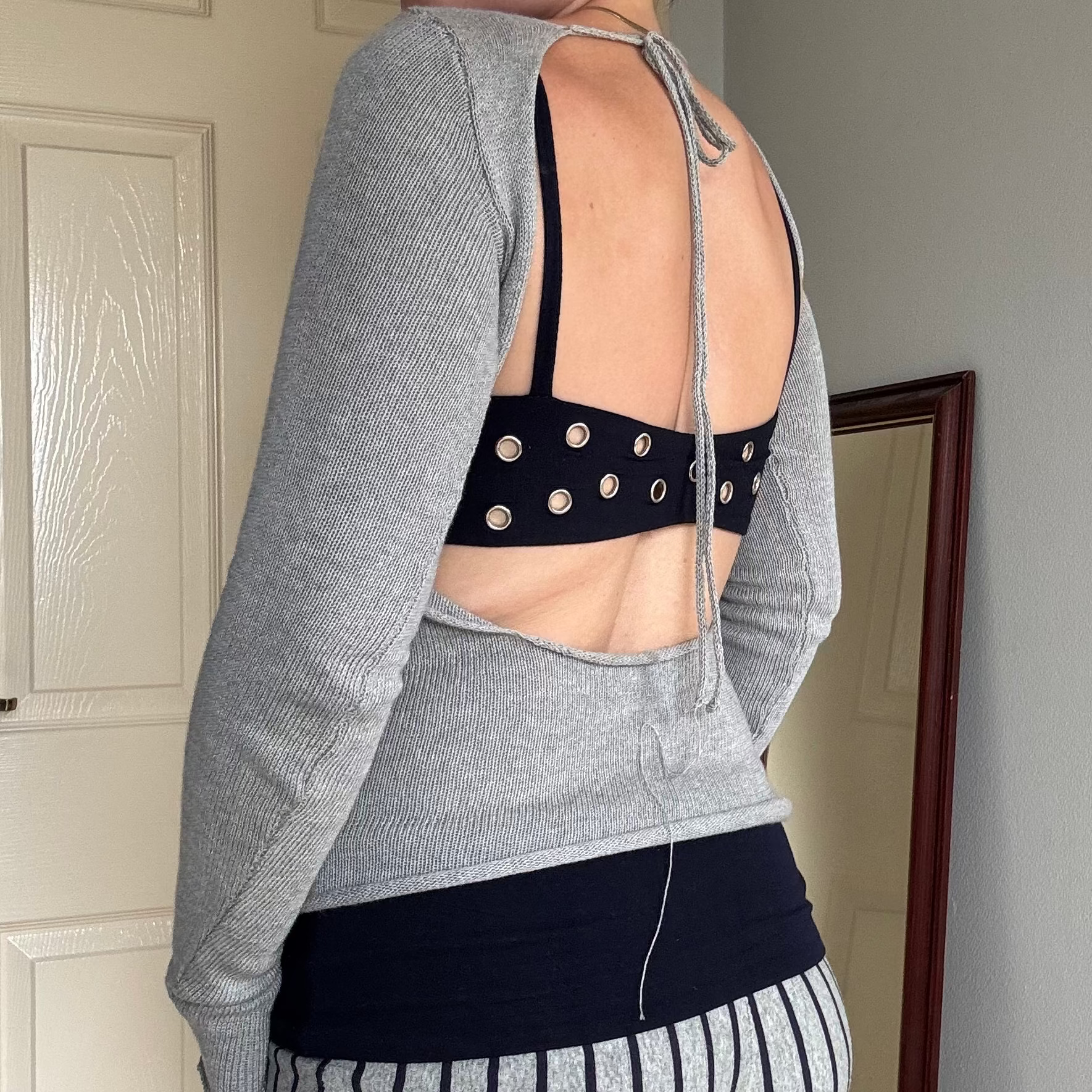 Person wearing a gray knit long sleeve backless top with striped shorts.