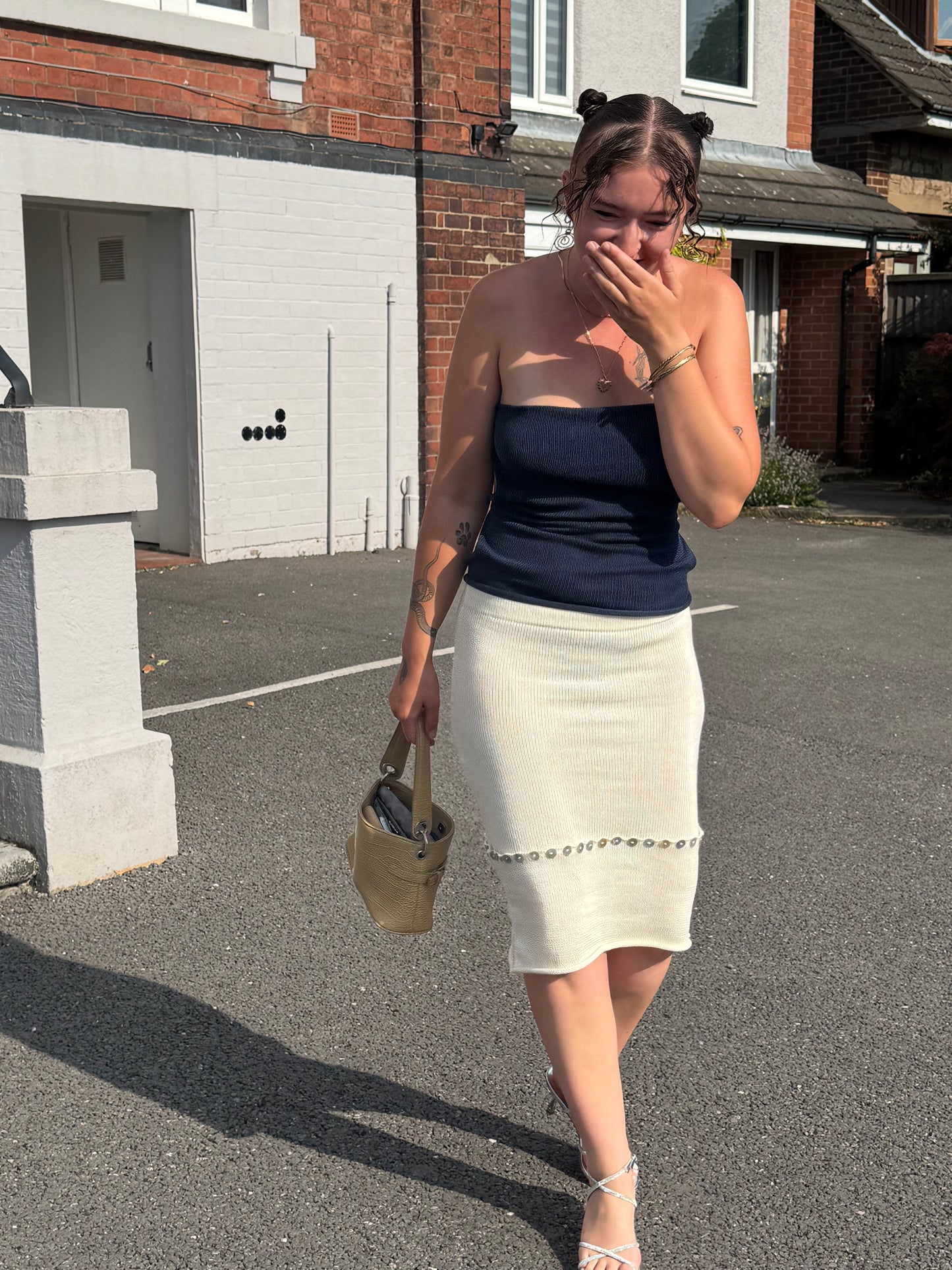 Person wearing a versatile white knit midi skirt with pearl button details.