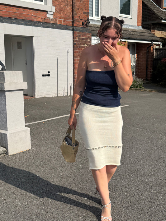Person wearing a versatile white knit midi skirt with pearl button details.