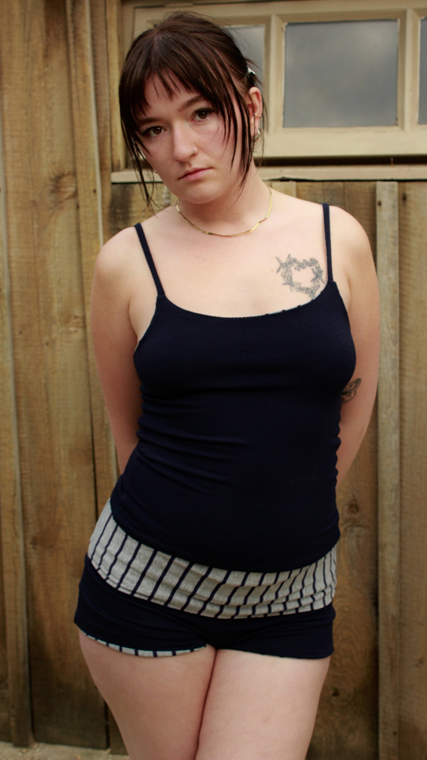 Person wearing navy blue and grey stripe reversible shorts with wide waistband and navy cami top.